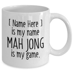 May include: White ceramic coffee mug with black text that reads "[ Name Here ] is my name MAH JONG is my game."