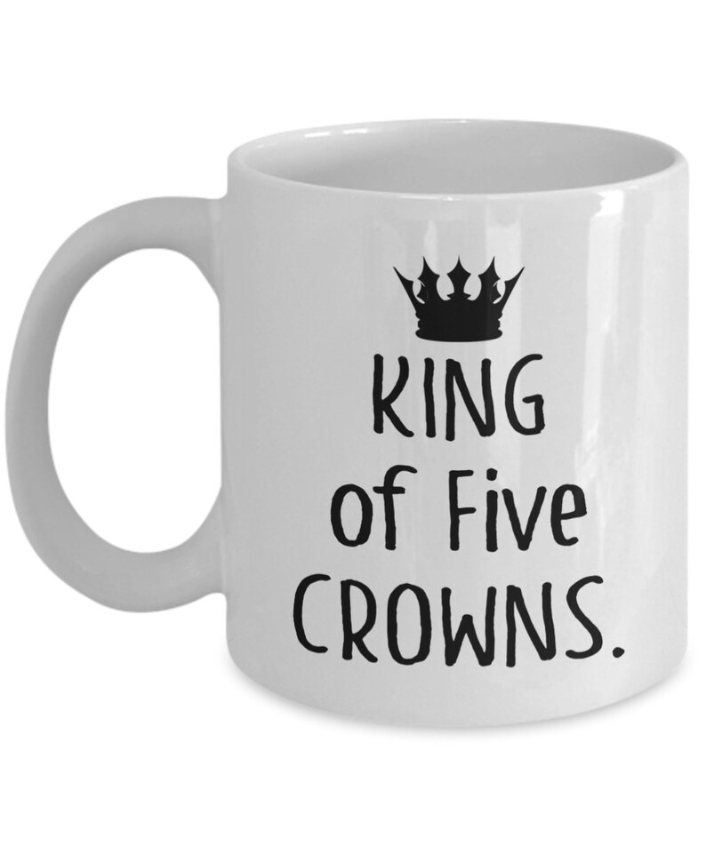 May include: White ceramic mug with a black crown and the text "King of Five Crowns."