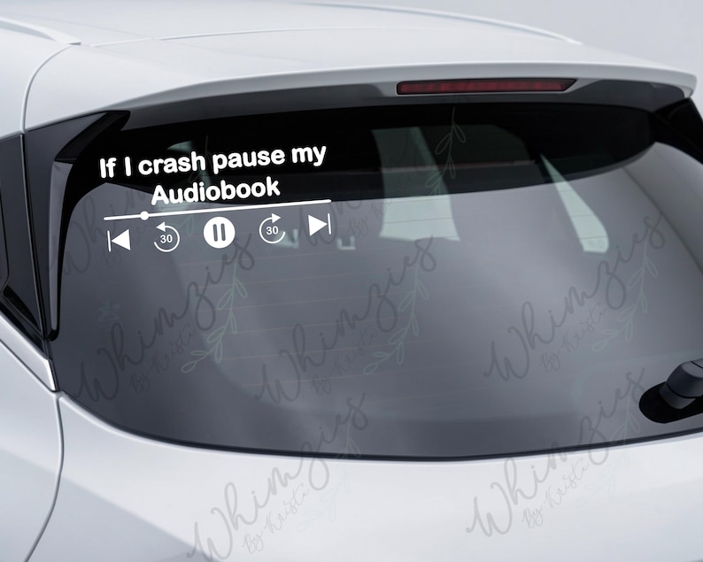 May include: White vinyl car decal with the text "If I crash pause my Audiobook" and media player controls. The decal includes a play/pause button, rewind, and fast forward icons. The decal is applied to a car's rear window.