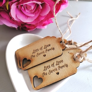 May include: Two wooden gift tags with a heart cut-out and the text "Lots of Love The Jarvis Family" engraved on them.