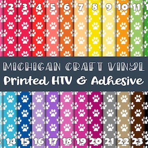 May include: A sheet of 24 different colored craft vinyl with a paw print pattern. The vinyl is labeled with numbers 1 through 24. The text "MICHIGAN CRAFT VINYL Printed HTV & Adhesive" is printed on a dark gray banner.