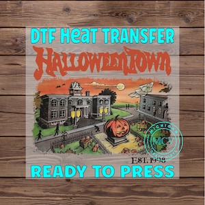 May include: DTF heat transfer featuring a Halloween Town design. The image includes a spooky town scene with a large jack-o'-lantern, buildings, and the text "Halloween Town." The words "Ready to Press" and "Est. 1998" are also included.