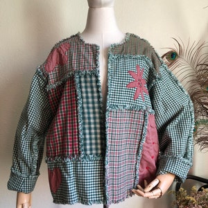 May include: A green and red patchwork jacket with frayed edges and embroidered flowers. The jacket is made of different plaid fabrics and has a relaxed fit.