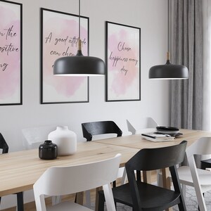 Peut inclure: Une salle &agrave; manger avec une table en bois et six chaises. Trois des chaises sont noires et trois sont blanches. Il y a trois impressions encadr&eacute;es sur le mur avec des citations inspirantes. Deux lampes suspendues noires pendent du plafond.