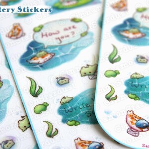 May include: A sheet of colorful, glittery stickers featuring cartoon fish, bubbles, and seaweed. The stickers have text that says "How are you?" and "Write back soon".