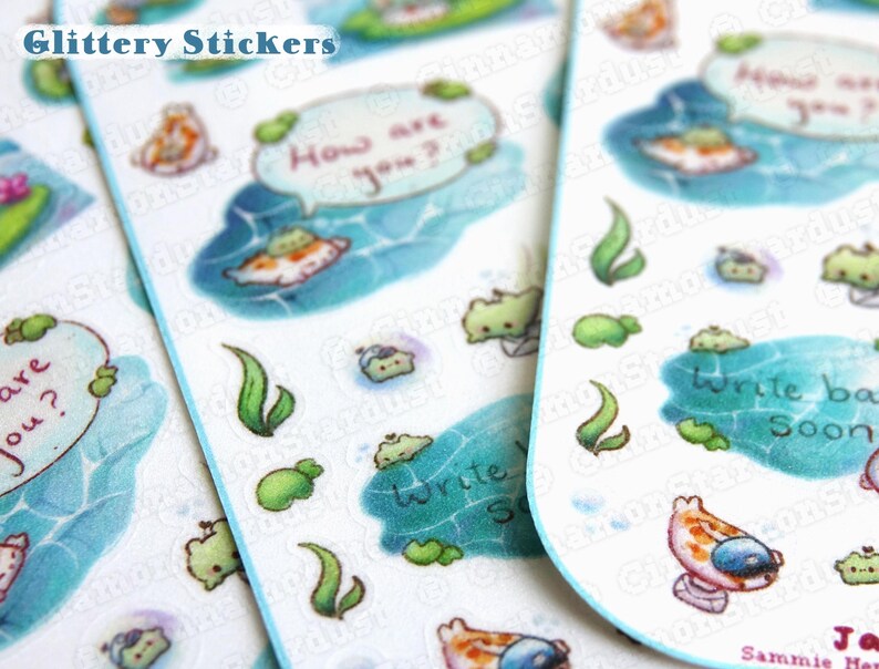 May include: A sheet of colorful, glittery stickers featuring cartoon fish, bubbles, and seaweed. The stickers have text that says "How are you?" and "Write back soon".