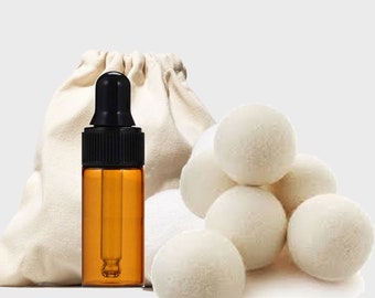 May include: An amber glass bottle with a black dropper, a small beige drawstring bag, and several white wool dryer balls. The items are arranged on a white background. The bottle is filled with a clear liquid.