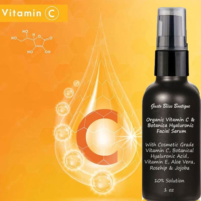 May include: A black bottle of organic Vitamin C & Botanica Hyaluronic Facial Serum with a dropper top. The bottle is labeled with the product name, ingredients, and a 10% solution concentration. The bottle is sitting on a yellow background with a large water droplet containing a red letter C.