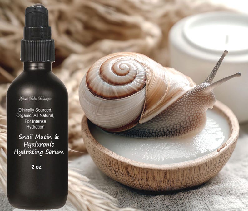 May include: A black glass bottle with a white label that reads "Ethically Sourced, Organic, All Natural, For Intense Hydration Snail Mucin & Hyaluronic Hydrating Serum 2 oz". The bottle is next to a snail on a wooden bowl.