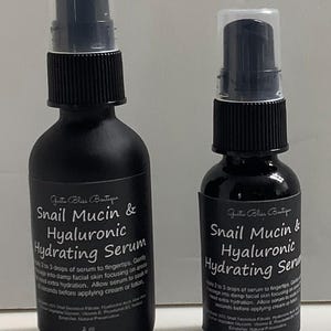 May include: Two black bottles of Snail Mucin & Hyaluronic Hydrating Serum. The larger bottle is 2 oz and the smaller bottle is 1 oz. Both bottles have a black label with white text.