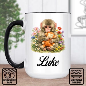 May include: White ceramic mug with a black handle and rim. The mug features a watercolor illustration of a monkey holding a stuffed monkey, surrounded by flowers. The name "Luke" is written in cursive. Dishwasher and microwave safe.