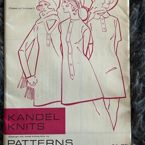 May include: Vintage sewing pattern featuring illustrations of women's fashion designs. The pattern, labeled "Overlay Plackets," includes drawings of dresses with button-up details. The cover has text that reads "Kandel Knits" and "Patterns from a Professional Knitting Mill."