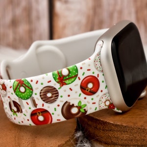 Könnte beinhalten: Weißes Apple Watch Armband mit einem Weihnachts-Donut-Muster. Das Armband zeigt grüne, rote und braune Donuts mit weißen Streuseln und roten und grünen Schleifen.