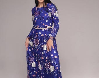 May include: A long, blue maxi dress with a floral pattern. The dress has a fitted bodice and a flowing skirt. The dress is adorned with a thin, sparkly belt.