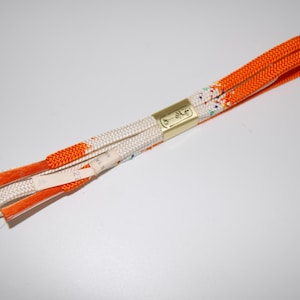 May include: A pair of orange and white cords with a gold tag that says "5-34-6".