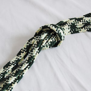 May include: A green and white braided rope tied in a knot. The rope is made of a soft, textured material.