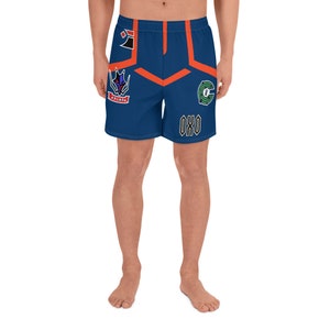 May include: Blue athletic shorts with orange and white accents. The shorts feature several patches with different designs, including a logo with the text "OX0".