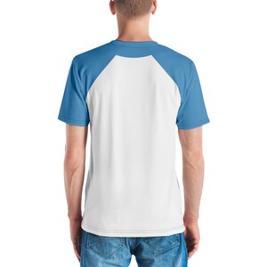 May include: A white and blue raglan t-shirt. The shirt has a white body with light blue sleeves and a light blue crew neck. The person in the image is wearing blue jeans.