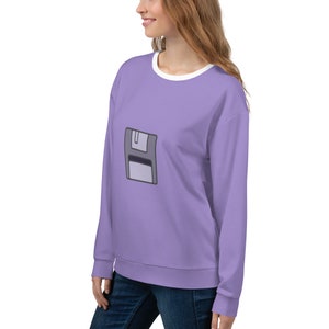 May include: A lavender sweatshirt with a white crew neck and a gray floppy disk icon on the front.