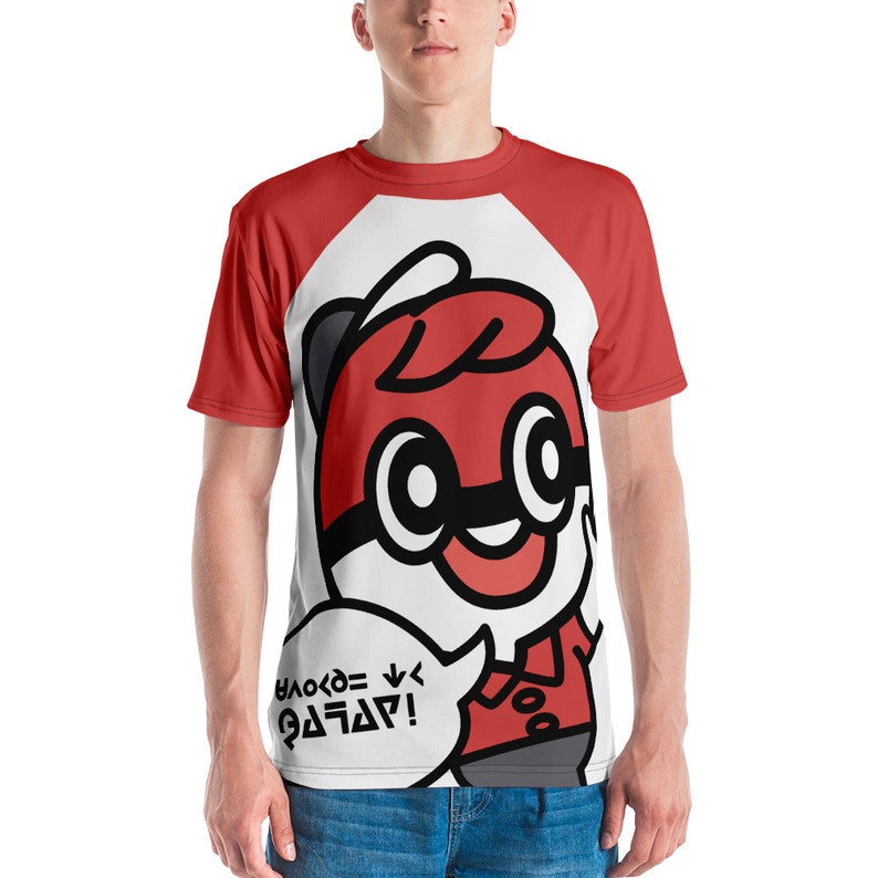 May include: Red and white raglan t-shirt featuring a cartoon character with a red and black design. The character has large eyes and a speech bubble with text. The shirt is worn by a person.