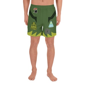 May include: Green athletic shorts with a black and yellow graphic design. The shorts feature a variety of logos and text, including "OKO" and a graphic of a hooded figure.