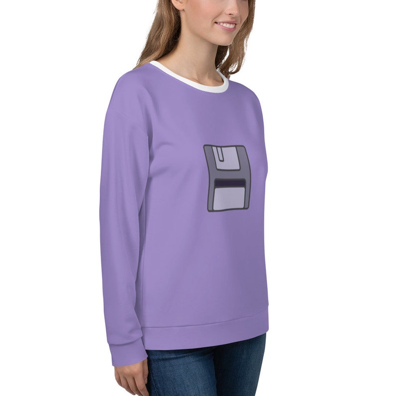 May include: A lavender sweatshirt with a white crew neck and a graphic of a gray floppy disk on the front.
