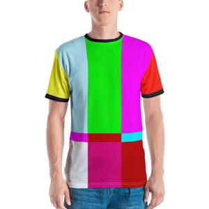 以下が含まれることがあります： カラフルな幾何学模様の半袖Tシャツ。シャツは黒い襟と袖に黒いトリムが付いています。パターンは、黄色、青、緑、ピンク、赤、白など、さまざまな色の正方形で構成されています。