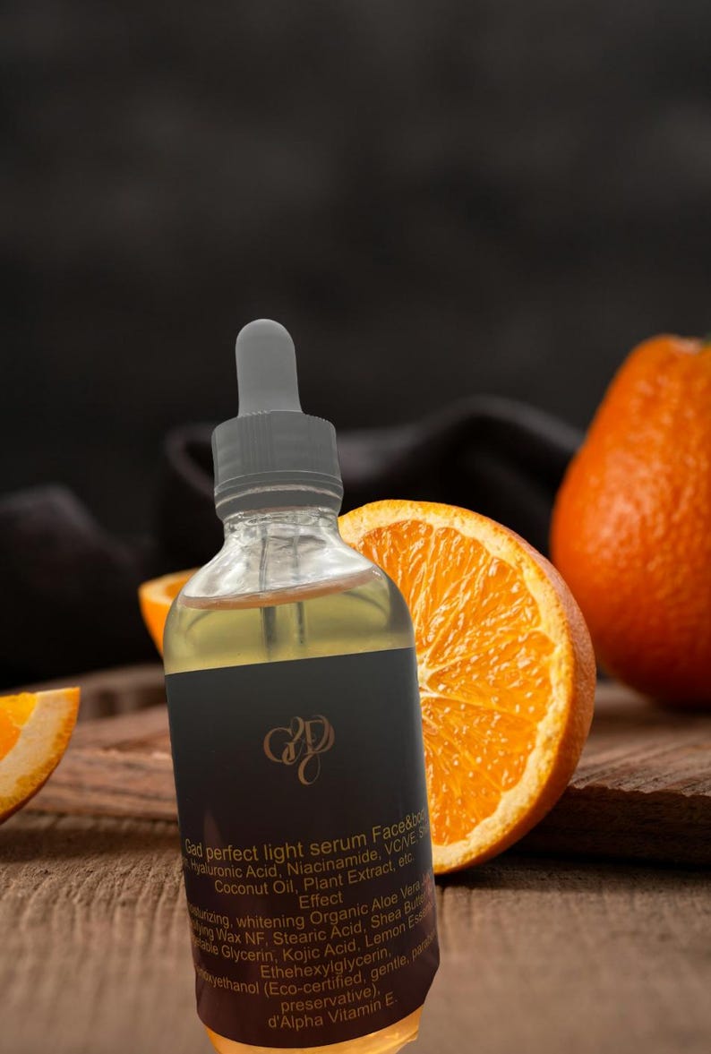 May include: A clear glass bottle with a dropper, filled with a yellow liquid, is the focal point. The bottle has a black label with gold lettering. Sliced oranges are arranged around the bottle on a wooden surface, creating a natural, fresh aesthetic.
