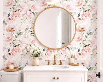 May include: A bathroom vanity with a white cabinet, marble countertop, and gold faucet, featuring a round mirror above. The wall is covered in floral wallpaper with pink roses and green leaves. A white vase with flowers sits on the counter.