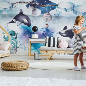 May include: A wall mural featuring a watercolor illustration of an underwater scene with orcas, a teal octopus, seashells, and icebergs. The design includes deep blue and white tones, creating a vibrant aquatic atmosphere for a room interior.