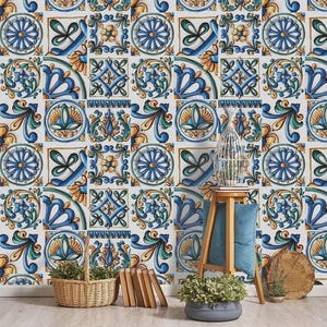 May include: Wallpaper featuring a repeating pattern of square tiles with blue, yellow, and green floral and geometric motifs. The design includes stylized petals, swirling leaves, and intricate scrollwork on a white background, creating a classic look.