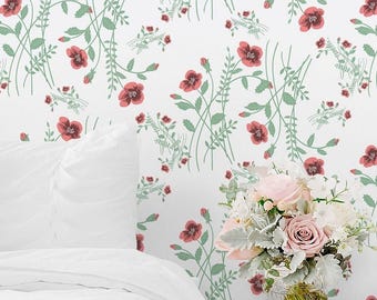 May include: A white wall covering featuring a repeating pattern of red poppy flowers and green stems. A white pillow and a white duvet are visible in the foreground, alongside a glass vase filled with a bouquet of pink and white flowers.