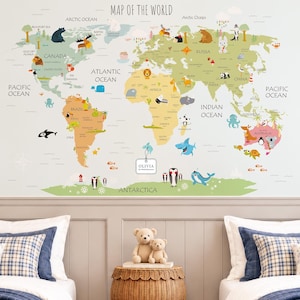 May include: A wall decal featuring a colorful world map with illustrations of animals and landmarks across continents and oceans. The text "MAP OF THE WORLD" is at the top, and a small white tag with the text "OLIVIA Our World Adventures" hangs near the center.