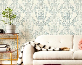 May include: Wallpaper featuring a repeating damask pattern in muted blue on an off-white background. The design displays intricate, symmetrical floral and scroll motifs with a weathered, distressed texture throughout the print.