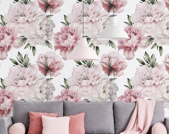 May include: A gray sofa with pink pillows and a pink throw blanket positioned against a wall covered in floral wallpaper featuring large, pale pink peony blossoms and dark green leaves, illuminated by two white pendant lights hanging from above.