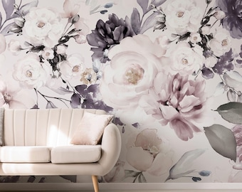 May include: A wall mural featuring a large-scale watercolor floral pattern in shades of dusty rose, muted purple, and charcoal gray against a light cream background, positioned behind a cream-colored upholstered sofa with a matching throw pillow.