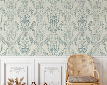 May include: Wallpaper featuring a repeating damask pattern in muted blue-grey on a cream background. The design consists of symmetrical floral and leaf motifs with a weathered texture, covering the wall above white wainscoting panels.