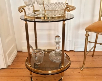attractive round Hollywood Regency bar cart in gold brass with 2 dark glass tops, 1960s. très classe!