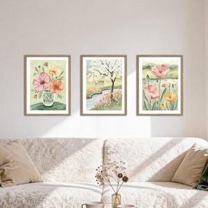 Peut inclure: Trois impressions d'art encadrées à l'aquarelle. Les impressions présentent des scènes florales et de paysages aux couleurs douces. L'une montre un vase de fleurs, une autre un arbre au bord d'une rivière et la troisième, un champ de fleurs. Les cadres sont de couleur marron clair.