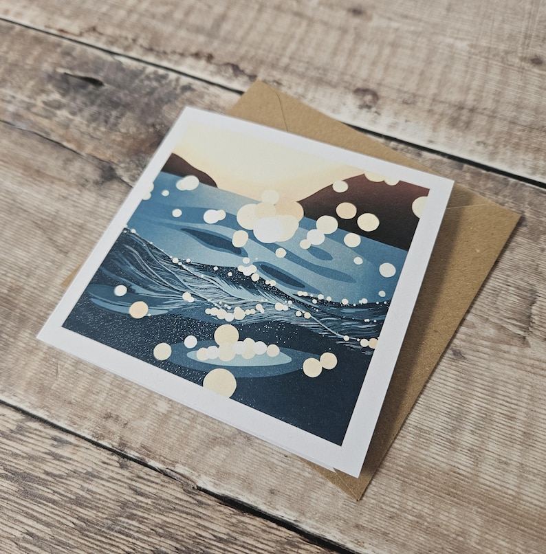 Pu&ograve; includere: Biglietto di auguri quadrato con un design di onde oceaniche blu e bianche. Il biglietto ha un bordo bianco ed &egrave; abbinato a una busta marrone. L'opera d'arte raffigura un paesaggio marino stilizzato con riflessi di luce.
