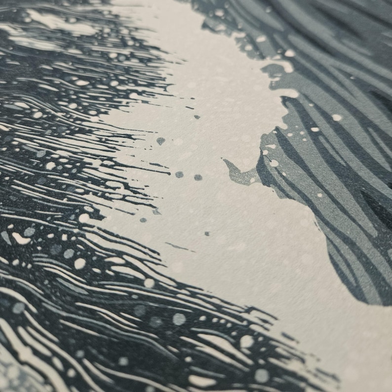 May include: A close-up of a print depicting a wave with white foam and dark blue water. The wave is breaking, with detailed lines and textures. The print has a minimalist style.