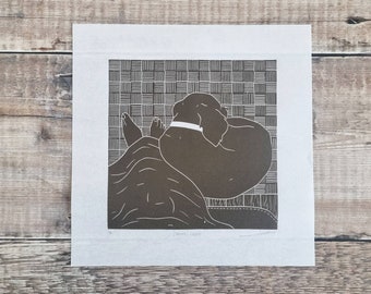 Comfy Cozy - Original Linoldruck eines Hundes, der sich in einer gemütlichen Nacht von den Füßen des Besitzers zusammengerollt hat