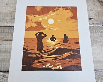 Chasing the Sun - Impression linogravure originale en édition limitée de trois personnes marchant vers la mer sous un soleil couchant