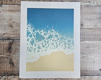 Original limitierter Linoldruck einer Welle, die sich am Strand bricht.