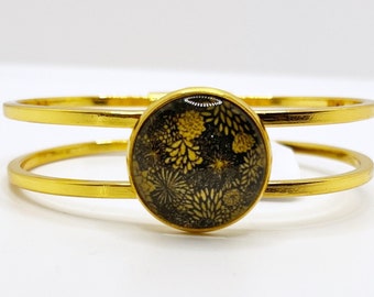 Gouden armband met 20mm cabochon met zwarte en gouden geometrische print. De armband gaat aan de voorzijde open door te kantelen. uniek handgemaakt