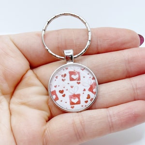 Porte clé argenté et blanc avec cabochon imprimé cœurs et paquets cadeaux rouge. paquet cadeau offert) idéal cadeau saint Valentin