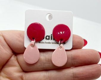 May include: A pair of earrings with a red circular top and a pink teardrop-shaped bottom. The earrings are attached to a white card with the brand name "KAPALAINE" and the text "Boucles d'oreilles fantaisies".