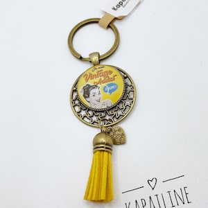 Bronze and dark yellow keychain with glass cabochon printed "I'm vintage addict" with small yellow pompom