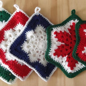 Può includere: Cinque presine all'uncinetto a forma di stella con motivi a fiocco di neve. Le presine sono di colore rosso, verde, bianco e blu.