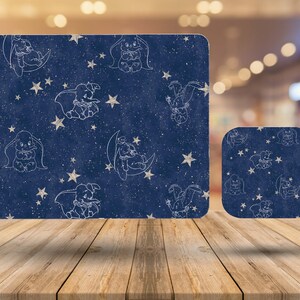 May include: A blue and white coaster set with a pattern of a baby elephant holding a star and a crescent moon. The set includes a large rectangular coaster and a smaller square coaster.